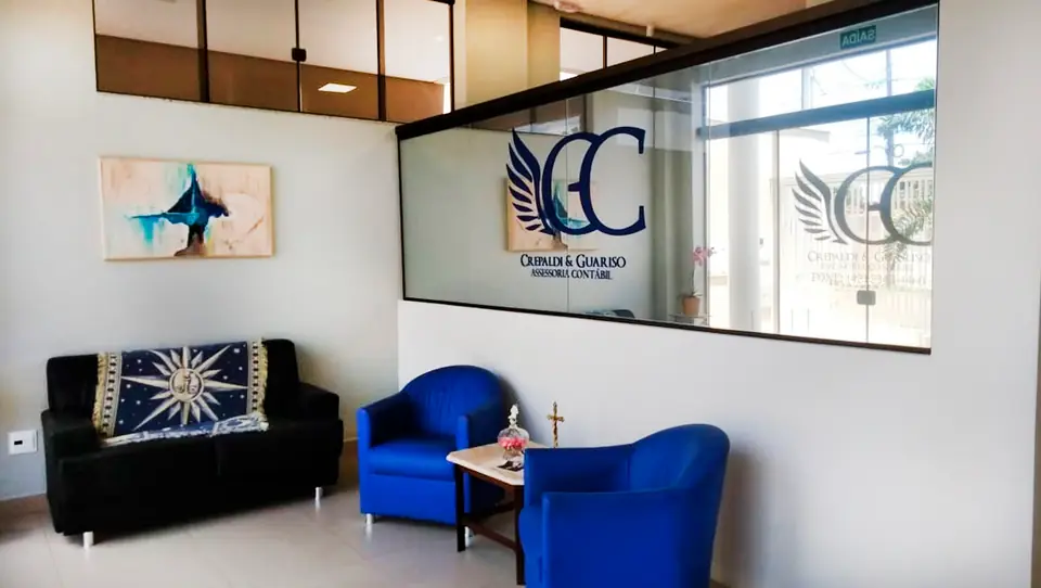 Recepção do escritório da Crepaldi & Guariso, com a logo na parede de vidro e poltronas azuis